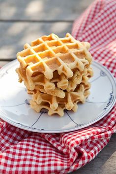 a stack of waffles on a plate with a red and white checkered cloth