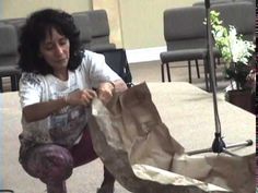 a woman kneeling down to cut something out of paper