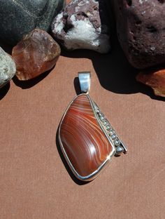 "Lake Superior Agate Pendant set in .950 Sterling Silver with solid silver back. Pretty red and white banding and decorative silver edge. Piece measures about 1.5\" x 1\" chain not included Our reviews will tell you, If you like it here, you'll LOVE it in person! GIVE IT A TRY! If not completely satisfied with your order, contact me right away and return the item within 7 days. FIND WHAT YOU LOVE: Use the \"Sections\" box (or \"Items\" list area) to see the categories. Or use the \"Search Items\" bar to search FUN terms like: eyes, tubes, water level, moon, Easter Island, double, gecko, heart and sale!  Great pictures and information coming to: www.instagram.com/agatejewelrybylarry twitter.com/agatesbylarry" Classic Agate Jewelry With Polished Finish, Classic Red Agate Jewelry, Artisan Agate Jewelry With Polished Finish, Carnelian Cabochon Pendant Jewelry, Elegant Carnelian Jewelry With Large Pendant, Classic Formal Agate Jewelry, Silver Carnelian Gemstone Jewelry, Polished Oval Carnelian Jewelry, Red Sterling Silver Jewelry With Large Stone