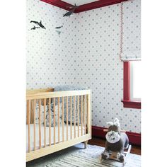 a baby's room with blue and white wallpaper, a crib, and a bird hanging from the ceiling