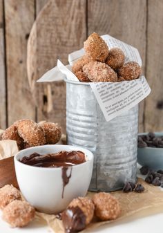 chocolate covered doughnuts in a bucket next to a cup of coffee and cookies