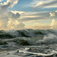 an ocean with waves crashing and clouds in the sky