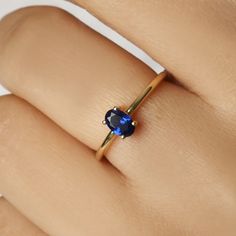 a woman's hand with a ring on it and a blue stone in the middle