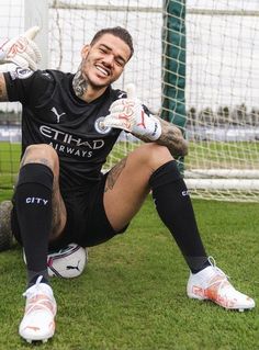 a man sitting on top of a soccer field next to a goalie's net