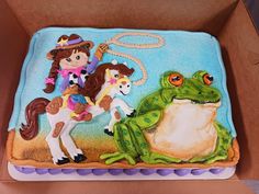 a birthday cake with a cowboy and frog on it's side in a box