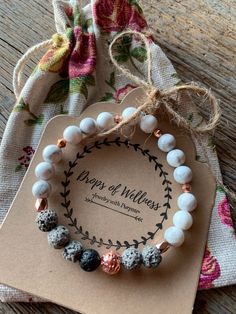 two bracelets with beads on top of a wooden table next to a tag that says,