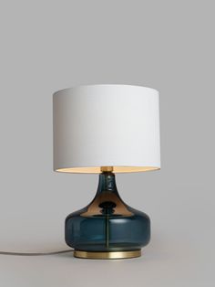 a blue table lamp with a white shade on the top and gold trim around the base