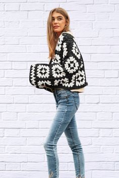 a woman is standing in front of a white brick wall holding a black and white handbag