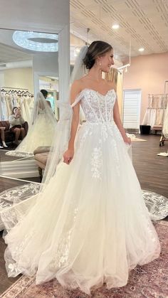 a woman standing in front of a mirror wearing a wedding dress