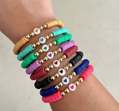 a woman's arm with different colored bracelets and evil eye charms on it