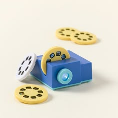 a blue toy camera with yellow and black buttons on it's side next to two smaller ones