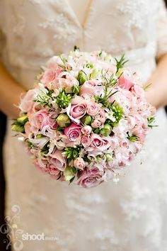 a bride holding a bouquet of pink flowers