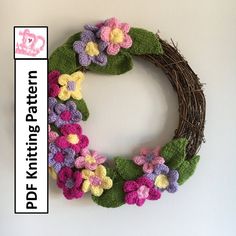 a crocheted wreath with flowers is hanging on the wall