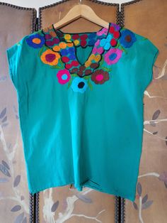 "70s lovely bright emerald green blouse with bright embroidery Black stitching at cuffs and around the V- neck Bust across 21\" (42\" around) Length 23\" Across shoulders 21\" Arm openings 16\" around **a couple of very light blue Mark's on left side. Little mend at bottom left side" Green V-neck Tops For Festival, Green Embroidered V-neck Blouse, Summer Green Blouse With Embroidered Neckline, Green Long Sleeve Tops With Embroidered Neckline, Green Long Sleeve Top With Embroidered Neckline, Green Bohemian Embroidered Top For Spring, Folk Style Green Embroidered Top For Spring, Spring Embroidered Green Blouse, Green Bohemian Top With Floral Embroidery