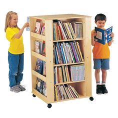 two children standing next to each other in front of a book shelf filled with books