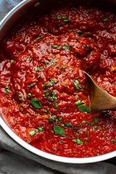 a wooden spoon is in a pot of marinara sauce