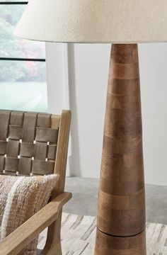 a lamp sitting on top of a wooden table next to a chair with a pillow