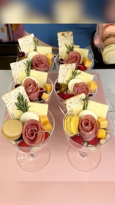 two wine glasses filled with different types of cheese and crackers on top of a table