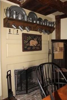 a dining room table and chairs in front of a fireplace with dishes on the mantle