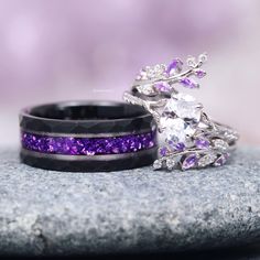 two wedding bands with purple and white stones on them sitting on top of a rock