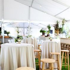 tables and stools are set up under a tent for an outdoor wedding or reception