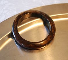 This fabulous Bakelite Bangle in a Brown Marbled hue is the perfect accessory for your vintage or contemporary outfit -- and sure to be a conversation starter. Rescued from an upscale estate sale near the Jersey Shore, this chunky bracelet is the real deal, testing positive as Bakelite using simichrome polish. The bangle measures approx. 3 1/4" in diameter with a 2 1/2" opening and stands 1/2" in height. The color is a dark marbled brown and the piece has a flat top and bottom. Based on the style, size, and positive Bakelite test, this piece is from the 1950s. This Bakelite Bracelet is in good vintage condition, used lovingly. There are scratches along the edges, from gentle use. For more photos, please contact me. And for more Vintage Bakelite Bracelets, like those in photo 7, please visi Vintage Bangle Bracelets For Formal Occasions, Retro Bangle Bracelets For Formal Occasions, Vintage Round Cuff Bracelet For Formal Occasions, Vintage Cuff Bracelet For Formal Occasions, Retro Adjustable Bangle For Formal Occasions, Adjustable Retro Bangle For Formal Occasions, Elegant Brown Cuff Bracelet For Formal Occasions, Elegant Brown Bangle For Formal Occasions, Formal Brown Cuff Bracelet Bangle