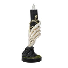 a skeleton hand holding a candle with a snake wrapped around it's arm on top of a black base