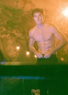 a shirtless man is standing in front of a television screen with his hands on his hips