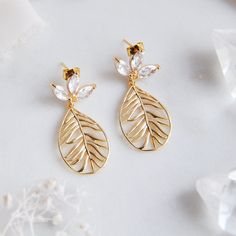 "Drift away with these tropical earrings to a destination wedding and dance the night away under the stars as the waves crash along the coast begging for a closer look at the beautiful boho beach goddess upon the shore. The dreamy boho vibes of the palm leaves are an enchanting tropical escape and accented with cubic zirconia flower earring posts for added sparkle. Whether gifting these golden palm leaf earrings to your bridesmaids or something special just for you, all of my jewelry arrives suitably gift wrapped ready for gift giving. Measurements: The length of the palm leaf earrings hang approx. 1.5\" long  Metals: 18k gold plated over 925 sterling silver earring posts 18k gold plated palm leaves Complete the look with a matching flower necklace: https://www.etsy.com/listing/1290030456/ Leaf-shaped Wedding Jewelry For Pierced Ears, Leaf-shaped Wedding Jewelry With Matching Earrings, Elegant Silver Jewelry For Destination Wedding, African Inspired Earrings, Boho Bridal Earrings, Flower Earrings Dangle, Beach Goddess, Tropical Earrings, Earrings Beach