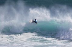 a man riding a wave on top of a surfboard in the middle of the ocean