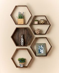 three hexagonal shelves with plants and pictures on them against a wall in the corner