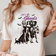 Let's Go Ghouls t-Shirts.Retro Halloween Shirt.Witch t-shirt.Spooky Witch Social Club Shirt.Halloween.Spooky Season.Gift for Halloween. Comfort Colors® Retro American Mama t-shirt. 4th July tee. Gift for American Mom. Vintage USA top. Freedom t-shirt for her. Gift for her.  Comfort Colors 1717 garment-dyed t-shirt  Item Details::.. - Fully customizable tee made 100% with ring-spun cotton. The soft-washed, garment-dyed fabric brings extra coziness to your wardrobe while the relaxed fit makes it a Retro Halloween T-shirt With Character Print, Witchy Halloween T-shirt With Graphic Print, Horror Graphic Print Top For Costume Party, Gothic Halloween T-shirt With Letter Print, Gothic White T-shirt For Halloween, White Gothic T-shirt For Halloween, Spooky Witch, American Mom, Vintage Usa