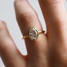 a woman's hand with a yellow gold ring on it and a diamond in the middle