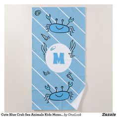 a blue beach towel with crab and letter m on it