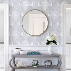 a console table in front of a wall with a mirror and vase on the top