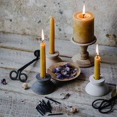 some candles are sitting on a table with scissors and other items around them, including one candle