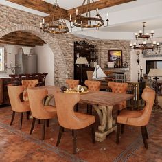 a large dining room table and chairs in front of a brick wall with arched doorways