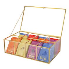 a gold box with six compartments filled with different types of teas and coffee bags