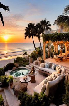 an outdoor living area with couches and tables next to the ocean at sunset or sunrise