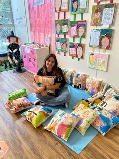 a woman is sitting on the floor with many pillows and toys in front of her