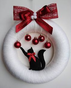 a wreath with ornaments hanging from it and a cat decoration on the front door hanger