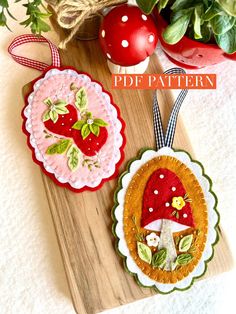 two handmade christmas ornaments sitting on top of a wooden cutting board next to potted plants