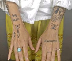 two hands with tattoos and rings on them