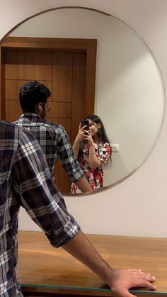 a man is taking a photo of his reflection in the mirror while he stands next to a woman