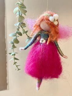 an ornament hanging from a tree with pink and orange hair on it's head