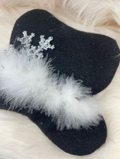 a black hat with white feathers and a snowflake brooch sitting on top of it