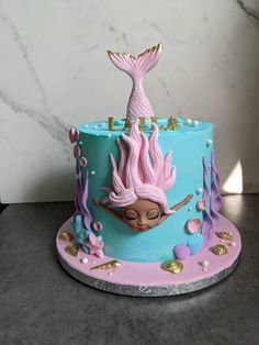 a blue and pink cake with a mermaid on top