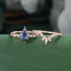 two gold rings with blue and white stones on top of each other in front of a green surface