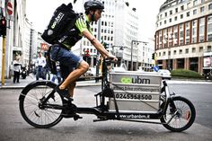 a man riding on the back of a bike with a cooler strapped to it's side