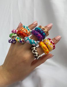 a woman's hand with five different colored rings on her fingers, all decorated with polka dots